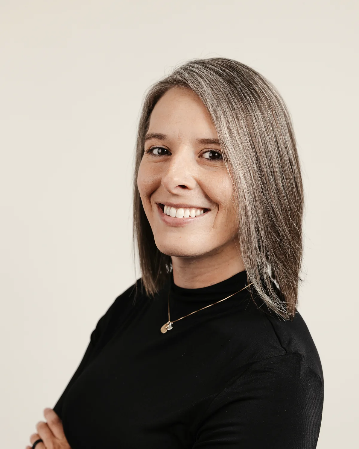 Portrait of Tasha Francis smiling in a black top against a gray studio backdrop