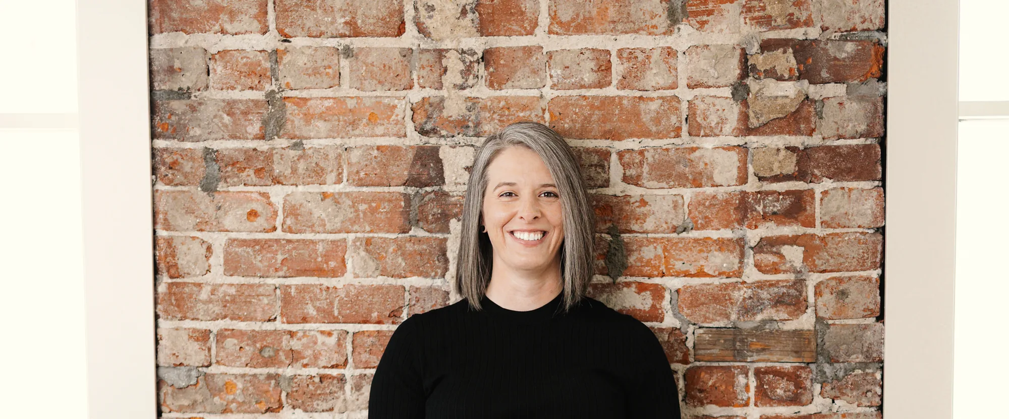 Tasha Francis smiling in front of an exposed brick wall