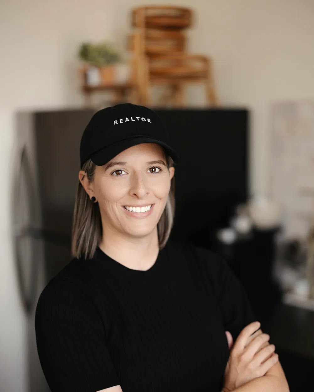 Tasha Francis with arms crossed wearing a black REALTOR cap
